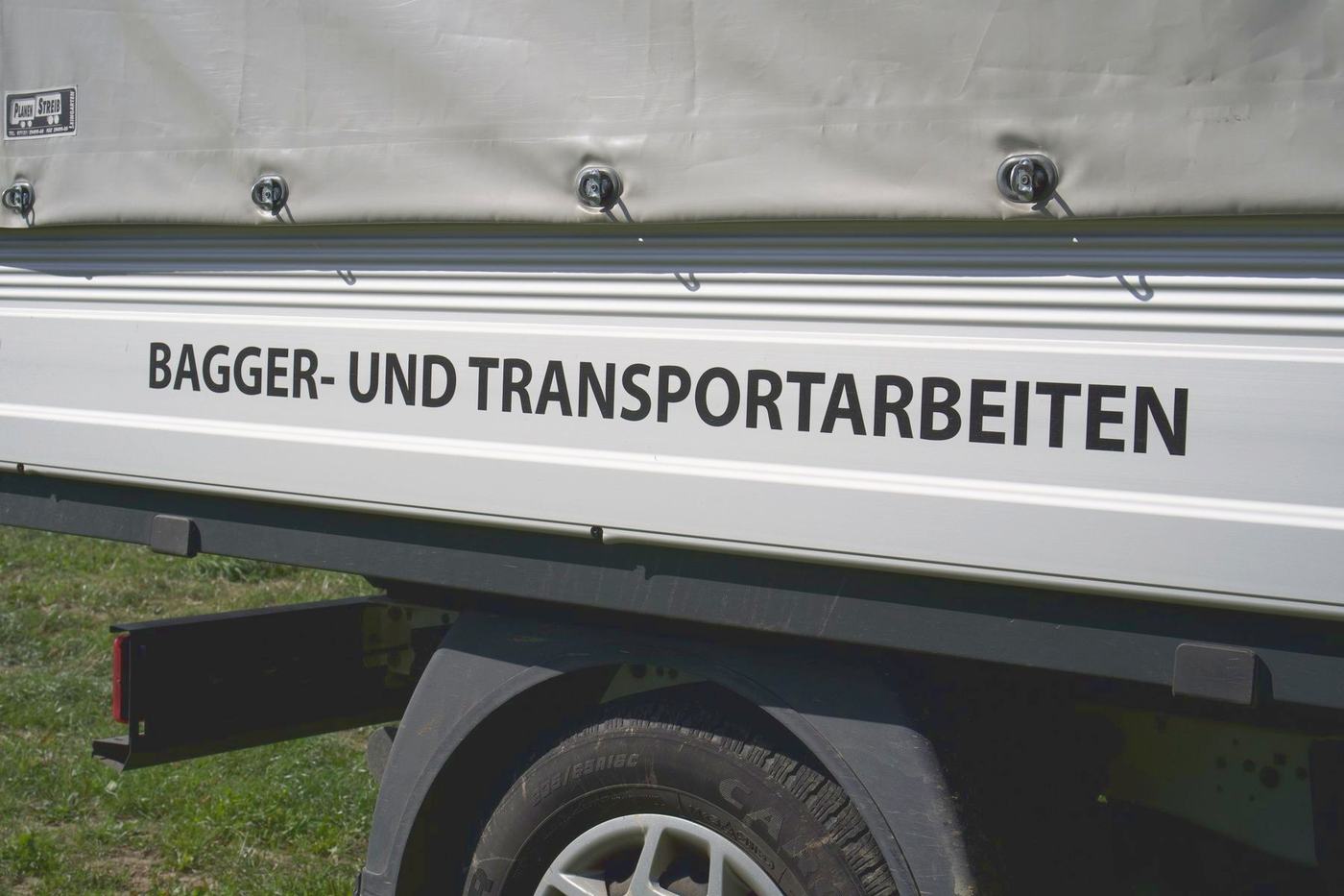 Schriftzug Baggerarbeiten und Transportarbeiten auf einem Fahrzeug