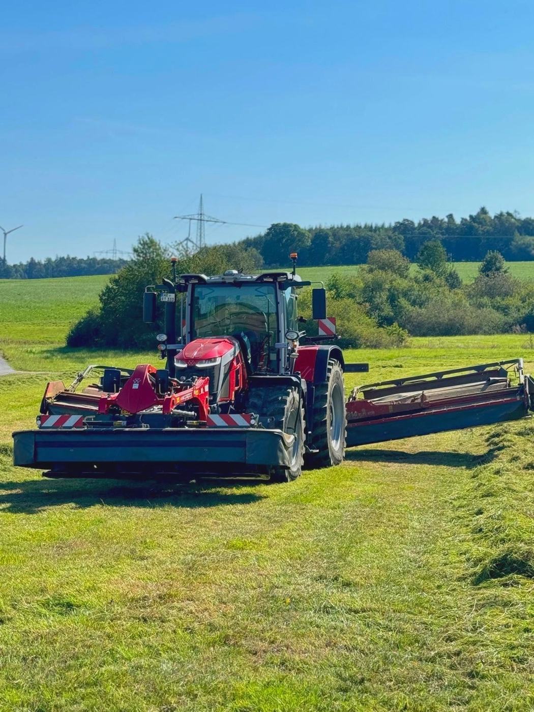 Traktor mit Schwader bei der Grünlandernte